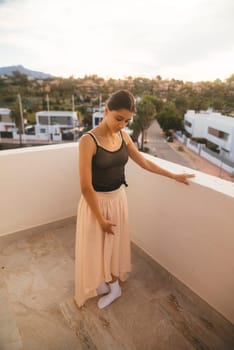 A graceful woman in a flowing skirt elegantly poses on a lovely balcony set against a beautiful scenic backdrop