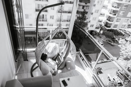 A peaceful and tranquil indoor balcony featuring a cozy swing chair, ideal for relaxation in urban life
