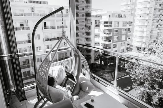 A chic and stylish balcony showcasing a luxurious hammock chair with beautiful city views to enjoy and relax