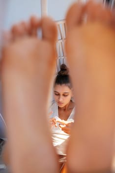 A peaceful and serene moment depicting feet in the foreground while a woman relishes her tranquil time indoors