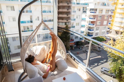 A woman is enjoying peaceful relaxation in a hammock on a stylish balcony with beautiful city views