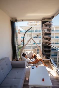 A person is enjoying their leisure time while relaxing in a contemporary hammock situated on a stylish balcony