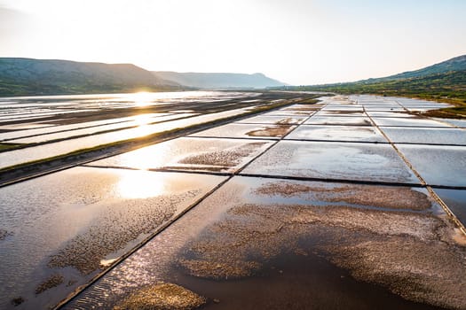 Sunrise over salt pans reflecting golden light in serene landscape