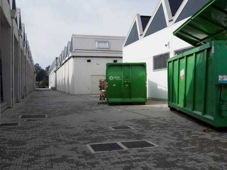 Cremona, Italy August 31st 2024 Large industrial green waste compactor machine with an electric cable plugged in, parked outdoors on a paved area