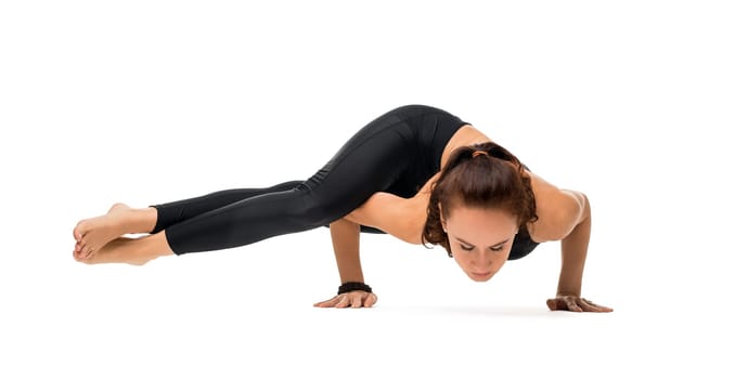 Beautiful brunette wearing black top and leggings practising her yoga routine making hand stand isolated on white