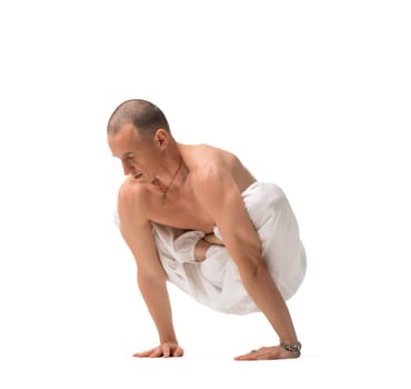 Mature shirtless muscular man wearing wide trousers doing yoga isolated on white