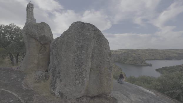 A person sits on a rock overlooking the deep canyon where the Esla and Duero rivers converge.