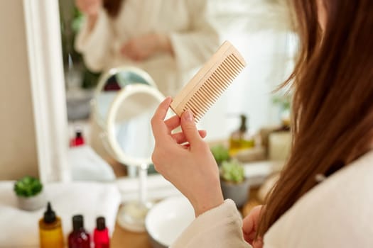Hair care, beauty and woman combing her hair with a wooden comb while taking care of herself. Hair care concept