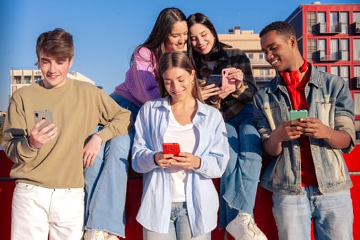 Group of friends using looking at their smartphones Multiracial teenagers browsing the internet with mobile phone on campus