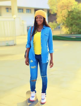 Stylish modern happy smiling young african american woman with skateboard in the city