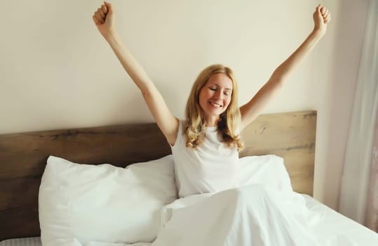 Healthy sleep, relaxed woman wakes up lying on the bed in bedroom at home