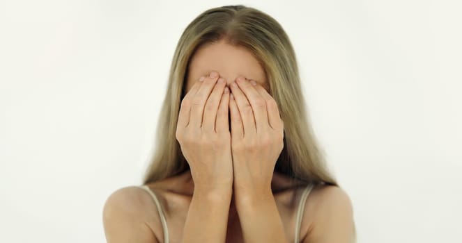Upset sad crying woman covering her eyes and face with her hands while experiencing depression, stress, fatigue, mental suffering