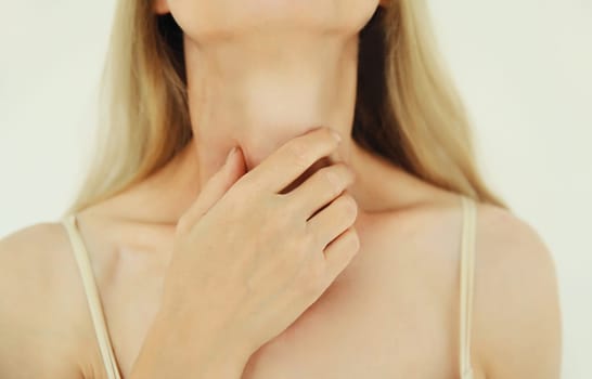 Close up sick exhausted mature woman suffering from acute sore in throat flu, touches her neck with hand, she feels bad