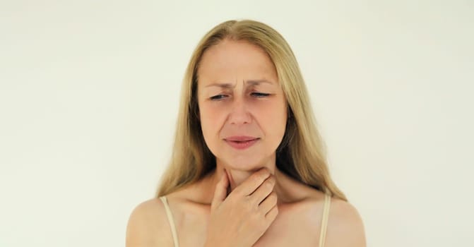 Portrait of sick exhausted mature woman suffering from acute sore in throat flu, touches her neck with hand, she feels bad
