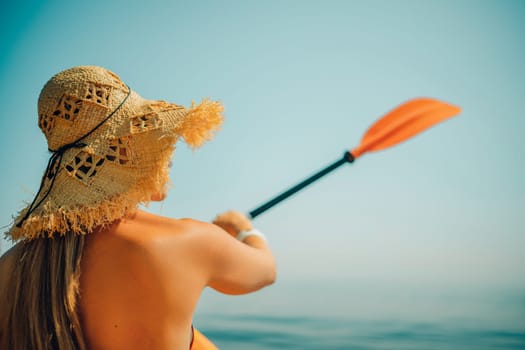 Woman in kayak back view. Happy woman with long hair in a swimsuit and hat floating in kayak on the sea. Summer holiday vacation. Summer holidays vacation at sea