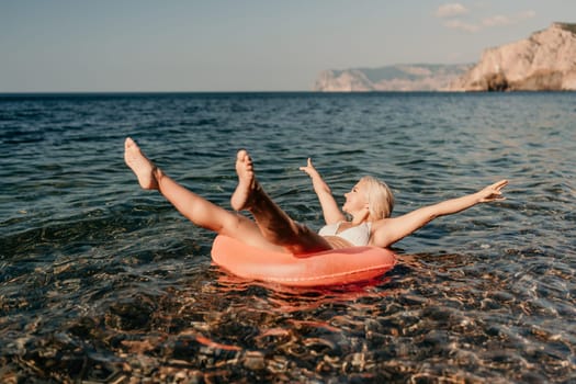 A woman is floating on a red inflatable raft in the ocean. She is smiling and enjoying the moment
