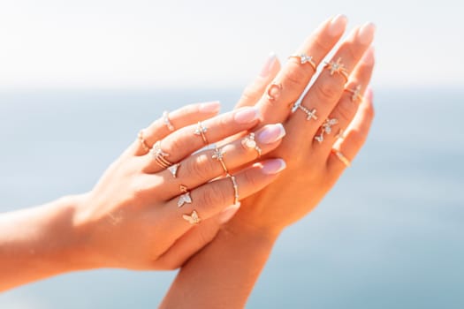 A woman is holding her hands up with a variety of rings on her fingers. The rings are of different sizes and shapes, and they are all placed on her fingers. Concept of elegance and sophistication