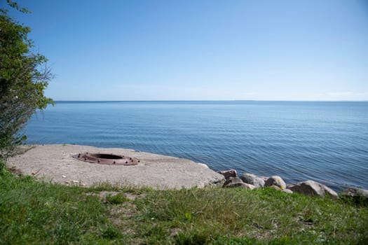 the blue water of the kattegat at trelde naes in denmark with blue water and sky and with The Foundation of metal on concrete of the old cannon.