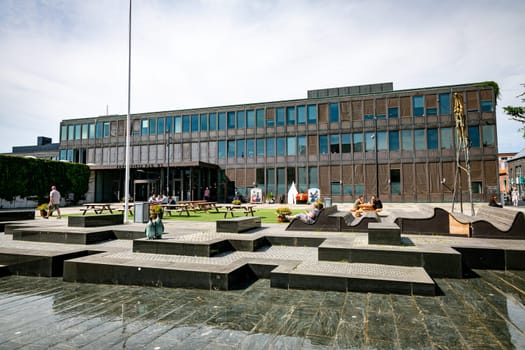 Fredericia, Jutland, Denmark, aug 13, 2024 - Contemporary town hall and square with people sitting on banks