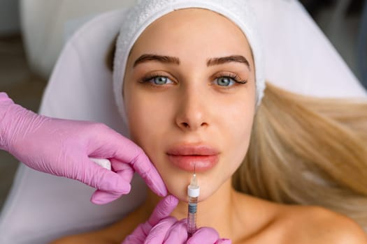 Injection procedure for lip augmentation, close-up. The cosmetologist slowly and carefully injects filler into the client lips. Advertising concept for facial care, youth and beauty.
