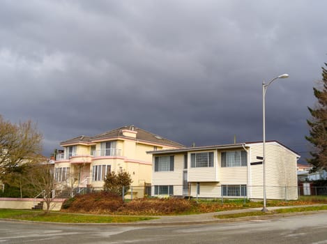 The street corner with two residential houses on stormy sky background.