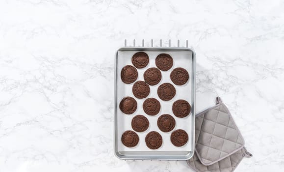 Flat lay. Cooling freshly baked chocolate cookies with chocolate hearts for Valentine's Day on a kitchen counter.