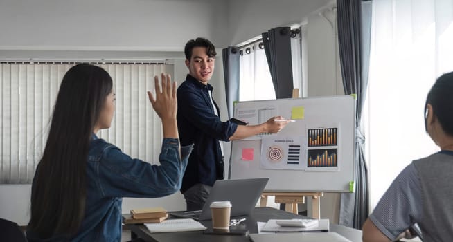 Young businessman explains work plan in meeting to teammates in conference room..