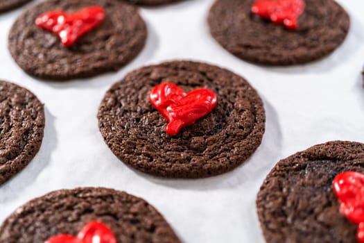 Decorating chocolate cookies with red chocolate hearts.