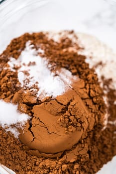 Mixing dry ingredients in a large glass mixing bowl to bake chocolate cookies with chocolate hearts for Valentine's Day.