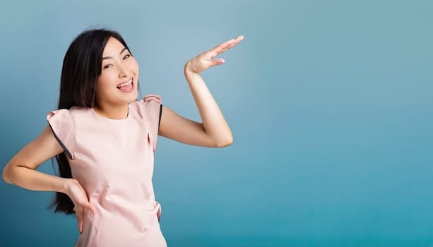 Portrait of young beautiful Asian lady smiling with cheerful expression, shows something amazing at blank space banner background poster wallpaper. AI Generative.