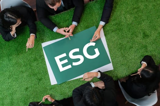 Top view panoramic banner ESG symbol on green grass meeting table with group of diverse business people planning marketing with eco-friendly awareness as environmental social governance concept.Quaint