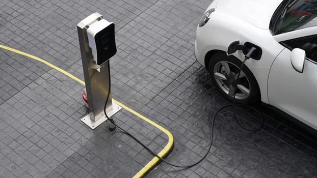 Progressive innovation urban electric on-street charging station with electric vehicle battery being charged with green energy for environmental concern in order to reduce CO2 emission.