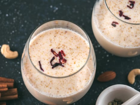 Thandai or Sardai cold drink made during Holi festival. Cold milk drink in glass, with ingredients - nuts and spices. Copy space
