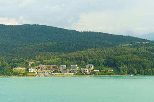 A peaceful lakeside resort emerges from the greenery, surrounded by majestic mountains, as the morning sun casts a gentle glow on the water's surface.