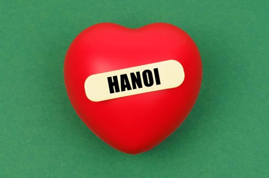 A striking red heart with Hanoi inscribed, capturing affection for the city, set against a lush green backdrop.