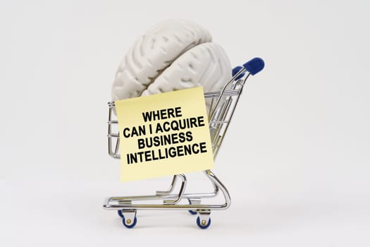 A unique shopping cart holds a brain alongside a note inquiring about acquiring business intelligence. Where can I acquire business intelligence