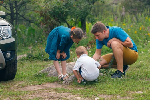 A man and two children joyfully explore a rocky area, discovering the beauty of nature with excitement