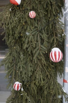 Christmas trees decorated with red balloons in front of the cafe entrance. Street New Year decorations.