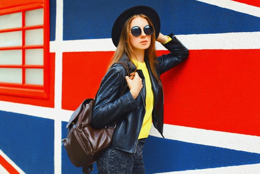 Portrait of beautiful young woman posing on english flag wall background