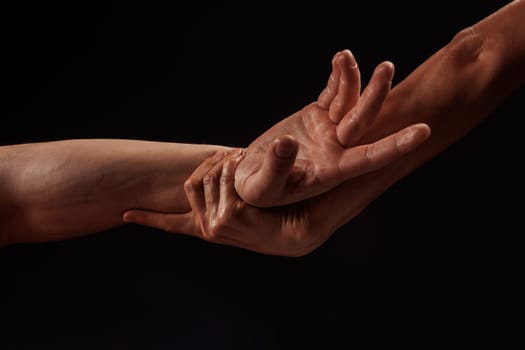 girl masseur doing hand massage to man on dark background close-up, beautiful relaxation massage, recovery