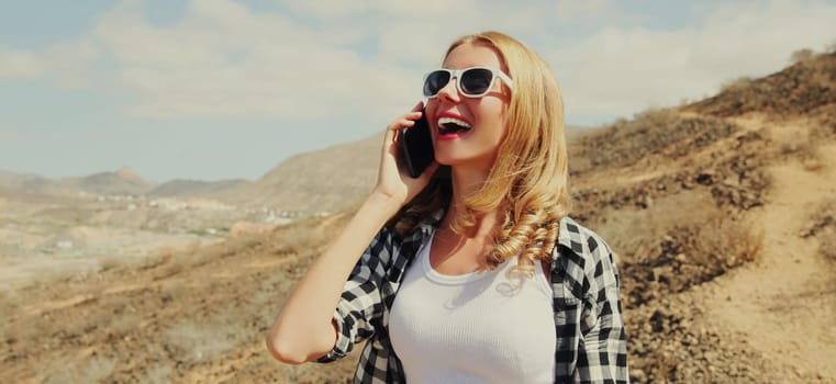 Happy woman calling on phone on a hiking trail on top of mountain, Tenerife, Canary Islands, Spain