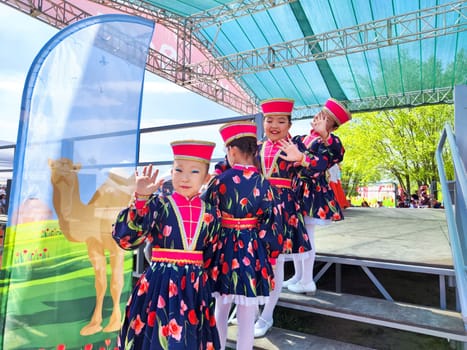 Elista, Kalmikia, Russia - April 21, 2024: Young performers in vibrant outfits gather on stage, excited to present their traditional dance at spring festival in Kalmykia