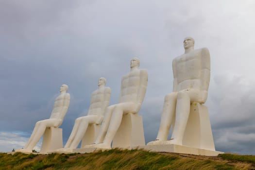 White Men statues, Esbjerg, Denmark. Four white men sitting looking at the sea near Esbjerg, Denmark. They are each 9 meters tall and made of white concrete.