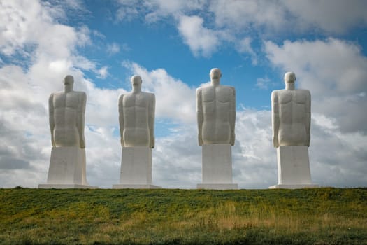 White Men statues, Esbjerg, Denmark. Four white men sitting looking at the sea near Esbjerg, Denmark. They are each 9 meters tall and made of white concrete.