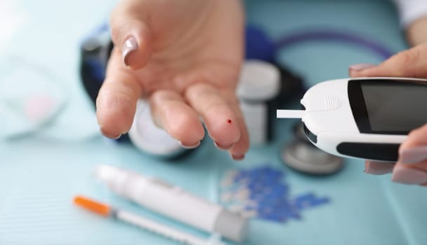 Close-up of doctor check blood sugar level of client use digital glucometer at hospital. Diabetes test for patient on appointment. Medicine, clinic concept