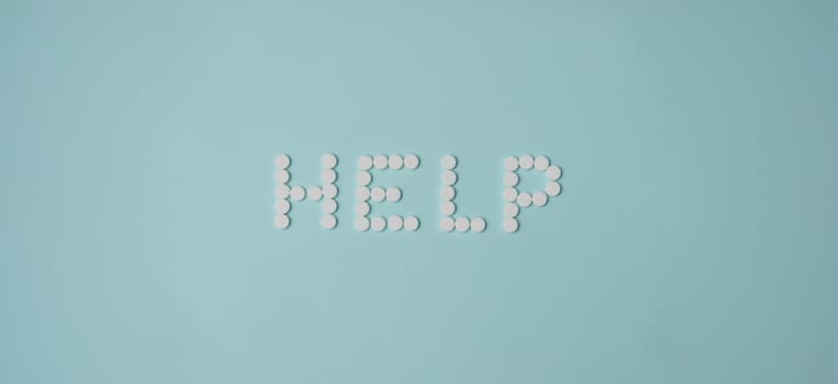 Top view of help lettering made with white round shaped pill, drug prescription for treatment. Pharmaceutical medicament, medicine, emergency, help concept
