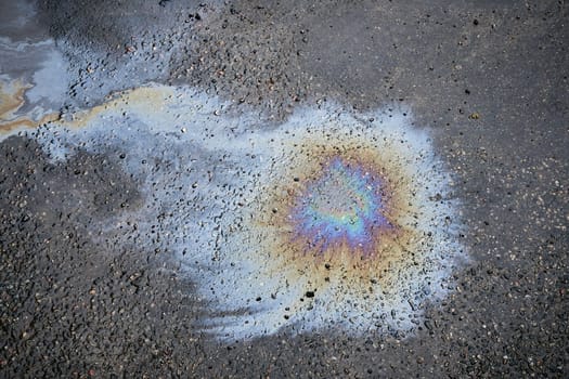 Fuel stain on wet asphalt. Colored stains from a gasoline leak on the road.