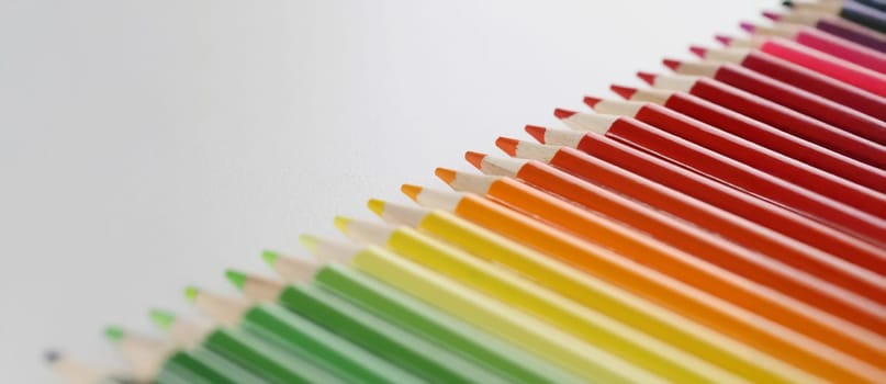 Close-up of pencils set perfectly placed in line on white surface for childs art. Crayon ready for drawing and create masterpiece. Creativity, art concept