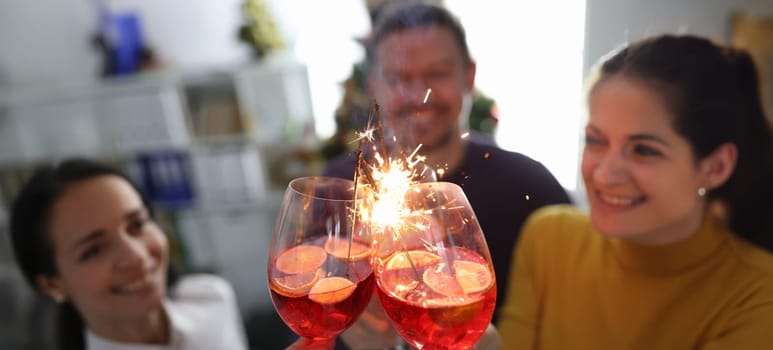 Friends celebrating at party with cocktails and sparklers. Celebrating birthday or new year concept