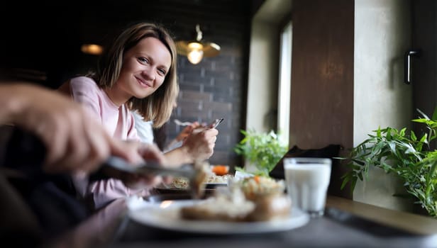 Young smiling woman is having lunch in cafe. Lunch break concept
